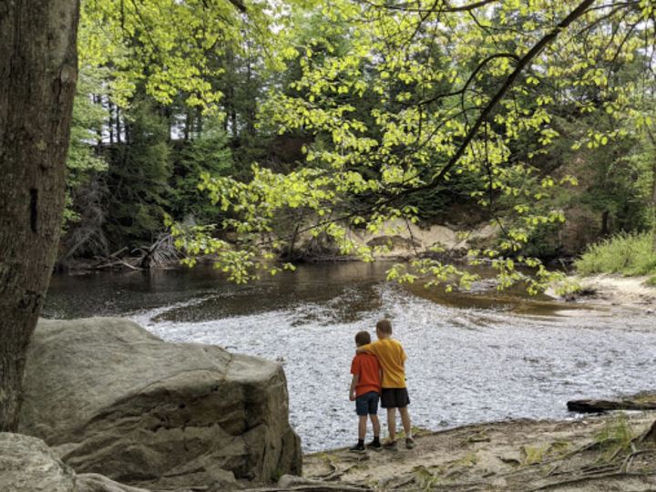 Two siblings hugging by the river in Merrimack, New Hampshire