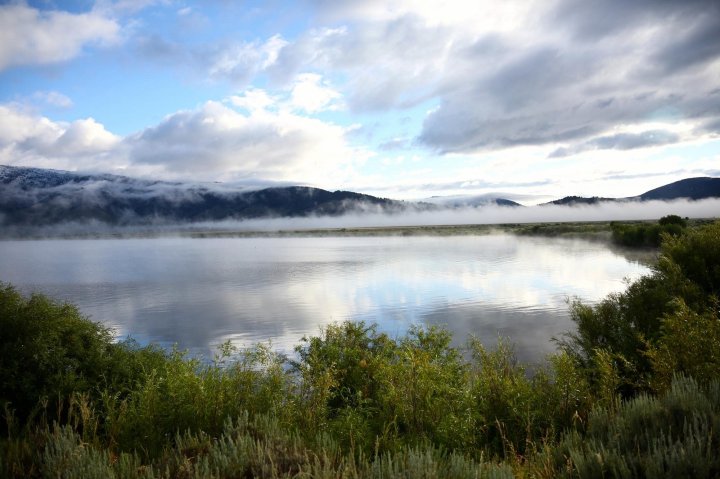 Colorful view of Henry's Lake in Idaho, with clouds reflecting in the blue water.