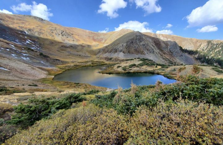 Bright blue waters of Lost Lake in New Mexico. The lake sits down in a small valley surrounded by low foothills and desert foliage