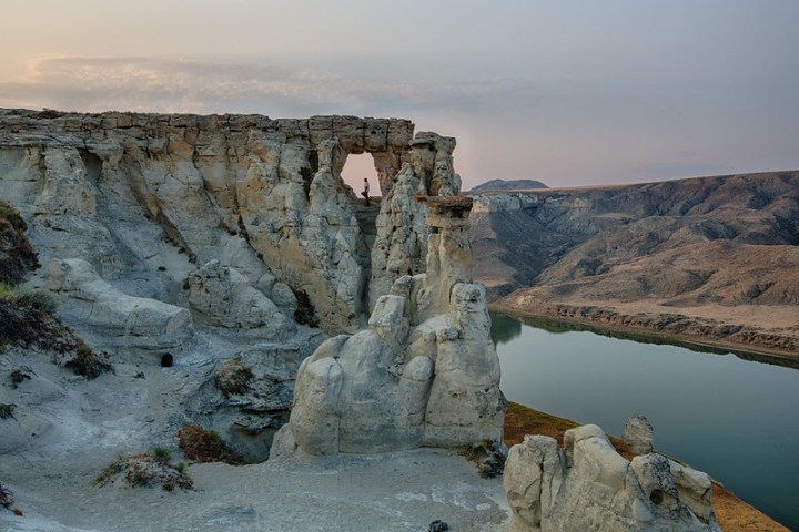 White and multicolored pillars of rock line the edge of the Missouri River Breaks National Monument. A person stands at the top of one of the White Cliffs.