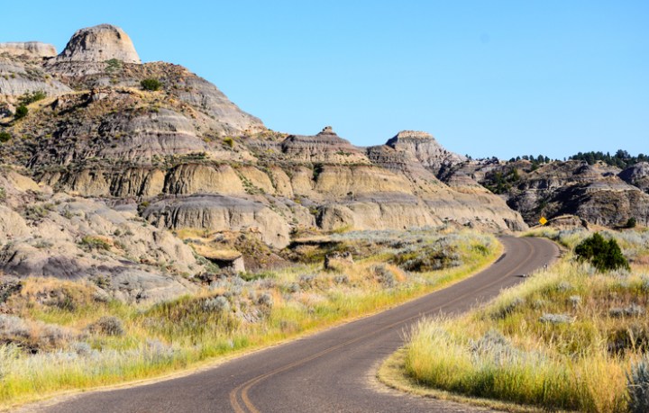 An empty road wraps around the edge of Makoshika State Park