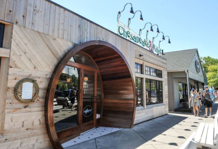 Exterior view of Chesapeake & Maine restaurant in Rehoboth Beach, Delaware. A large circular doorway leads inside. Chesapeake & Maine is the restaurant component of a Rehoboth Beach brewery and a stop on Delaware's Culinary Coast.