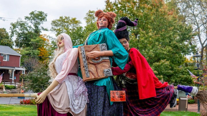 Three scarecrow withces sit atop a broom