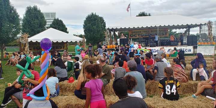 A group of people sit on haystacks in front of a stage.