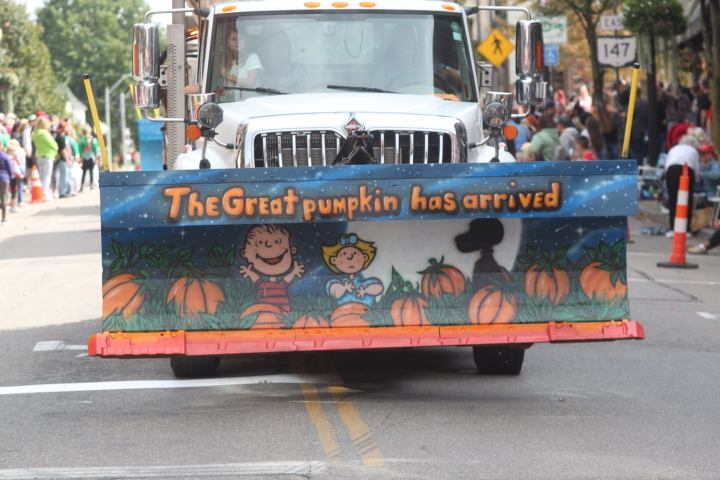 A plow truck with a picture of Charlie Brown that says the Great pumpkin as arrived