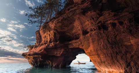 A lone kayaker exits a sea cave on The Apostle Island National Lakeshore in Wisconsin in Fall.