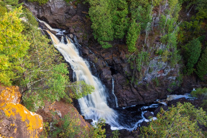 A tall cascading waterfall scenic landscape in autumn.