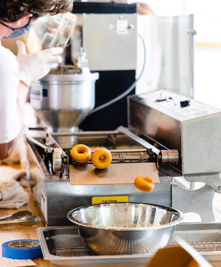 Fresh, hot, mini donuts fly off the conveyor into a catch bowl at Sons Donuts + Pops, a donut shop in Birmingham, Alabama.